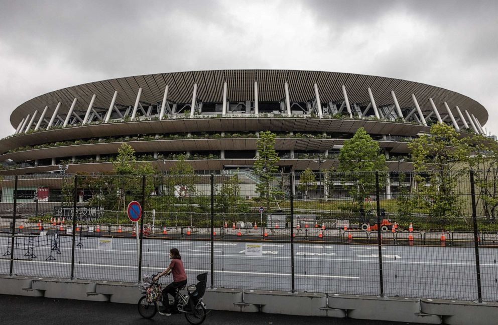 PHOTO: A woman cycles alongside a security fence surrounding the Olympic Stadium on July 8, 2021, in Tokyo, Japan.