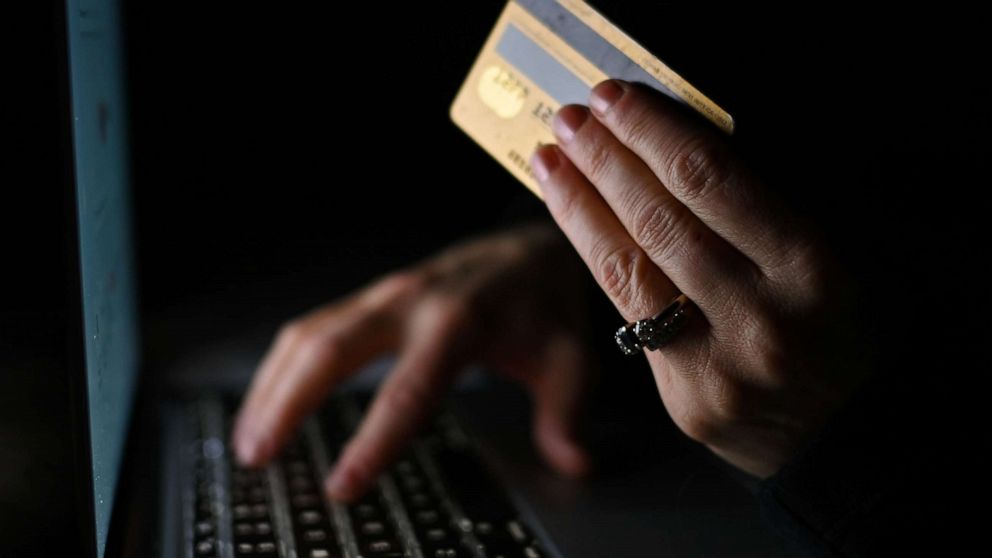 PHOTO: An illustrative image of a person holding a credit card while shopping online on a computer. 