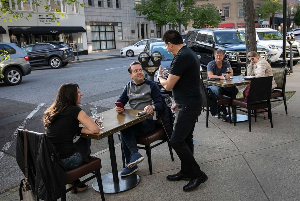 PHOTO: A server speaks with patrons at Douro restaurant on May 20, 2020 in Greenwich, Connecticut.