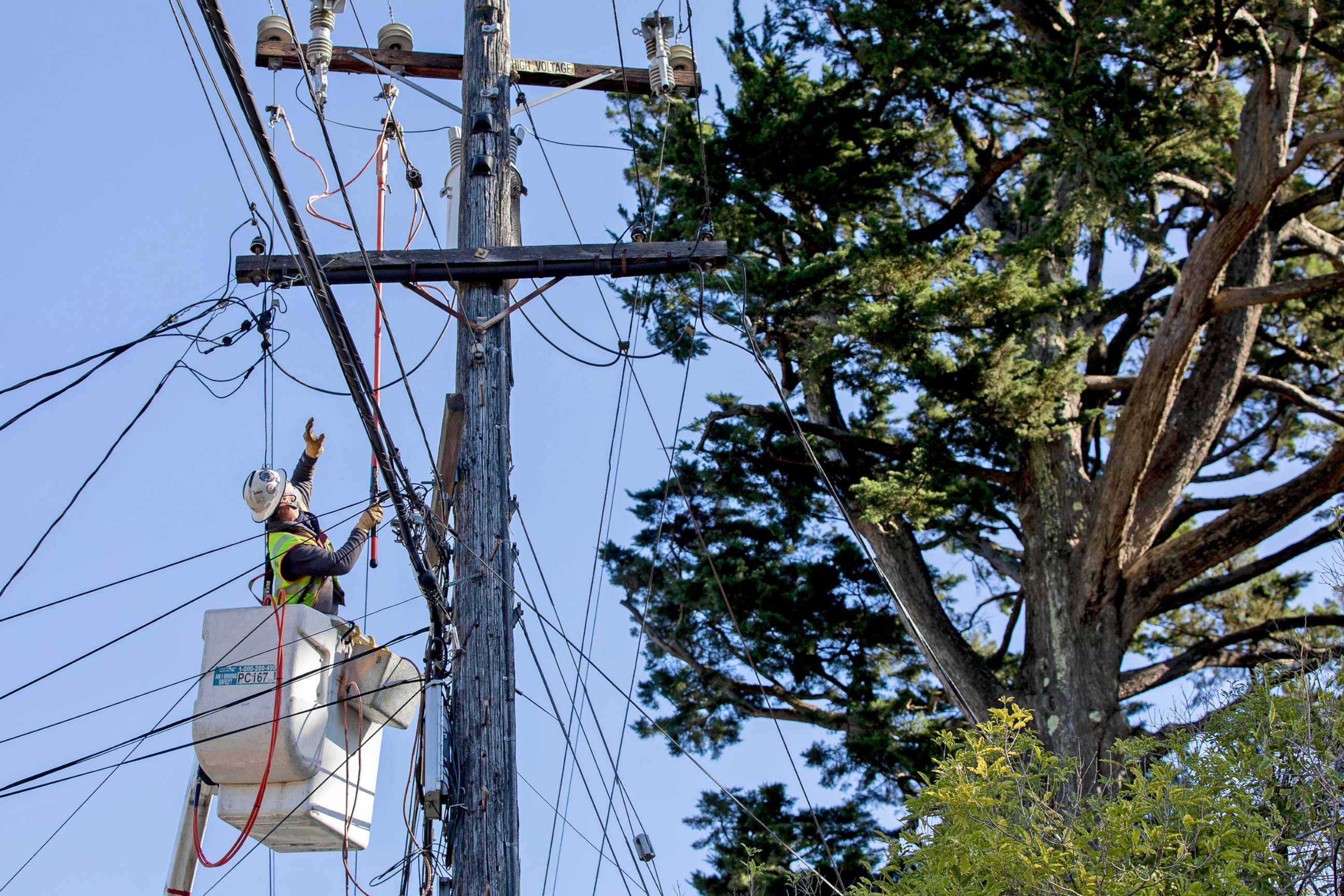 PHOTO: A PG&E employee works to deactivate power lines in order to repair others knocked down by a trees due to high winds in Oakland, Calif., Jan. 19, 2021.