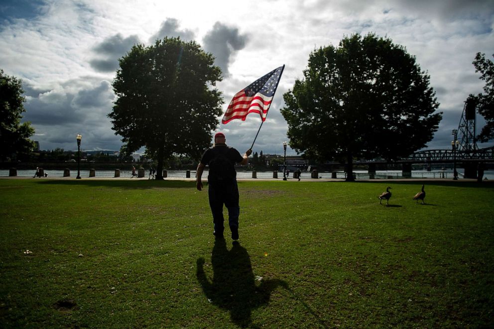 PHOTO: A member of the Proud Boys, who declined to give his name, carries a flag before the start of a protest in Portland, Ore., on Saturday, Aug. 17, 2019.