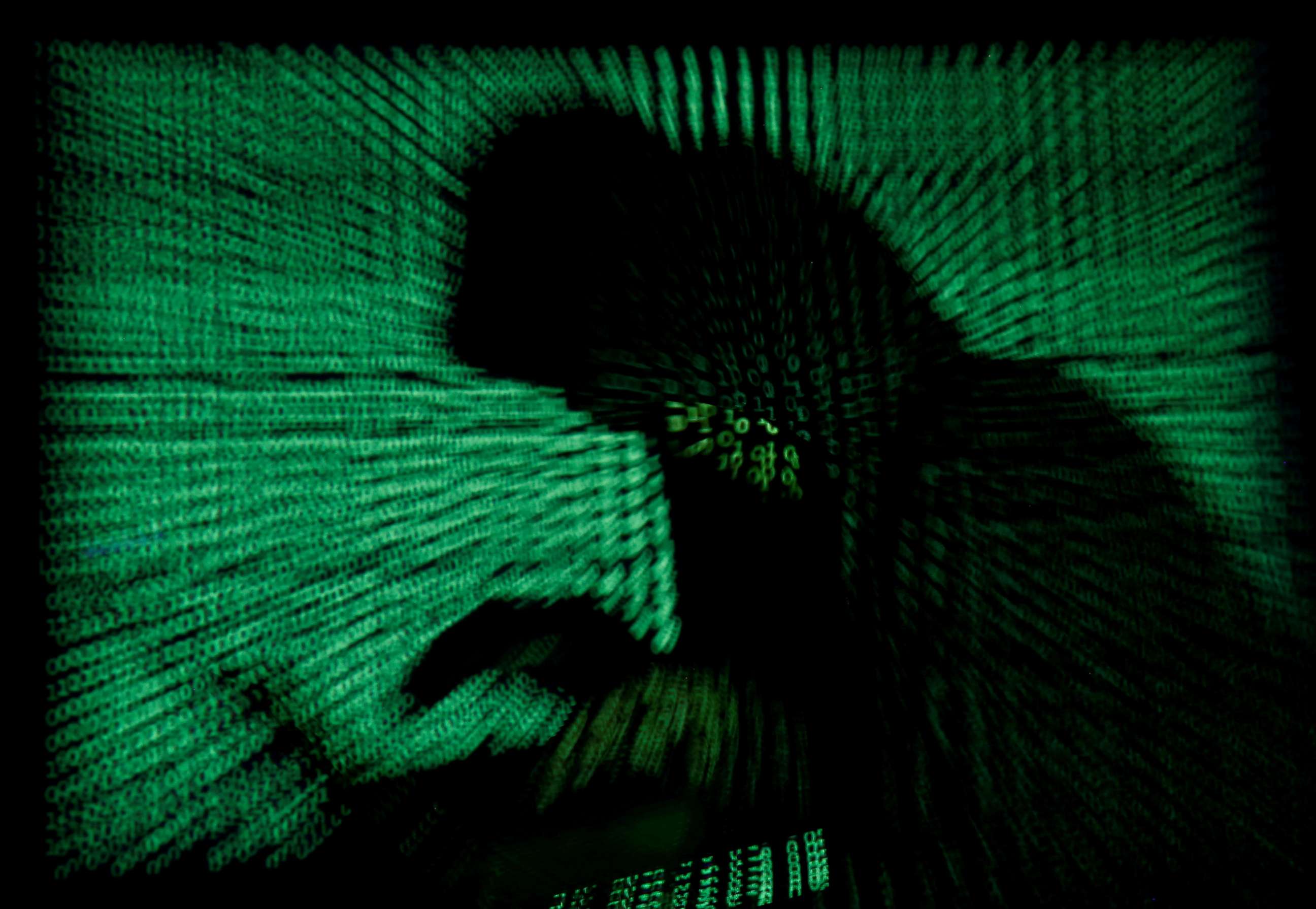 PHOTO: A photo illustration depicts a hooded person with a laptop computer as cyber code is projected, May 13, 2017.