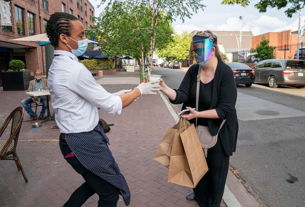PHOTO: Christy Schlesinger, right, picks up a carryout dinner order, May 29, 2020, as the District of Columbia loosens restrictions on restaurants that have been in place since March 25 because of the pandemic. 