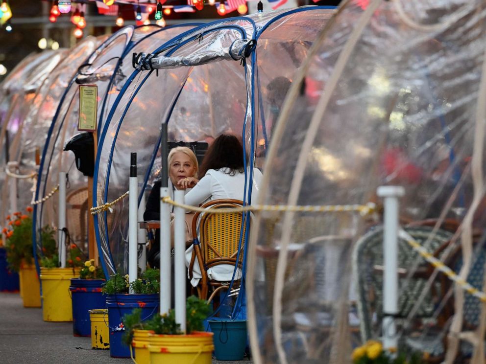 PHOTO: People dine in plastic tents for social distancing at a restaurant in Manhattan on October 15, 2020, in New York City.