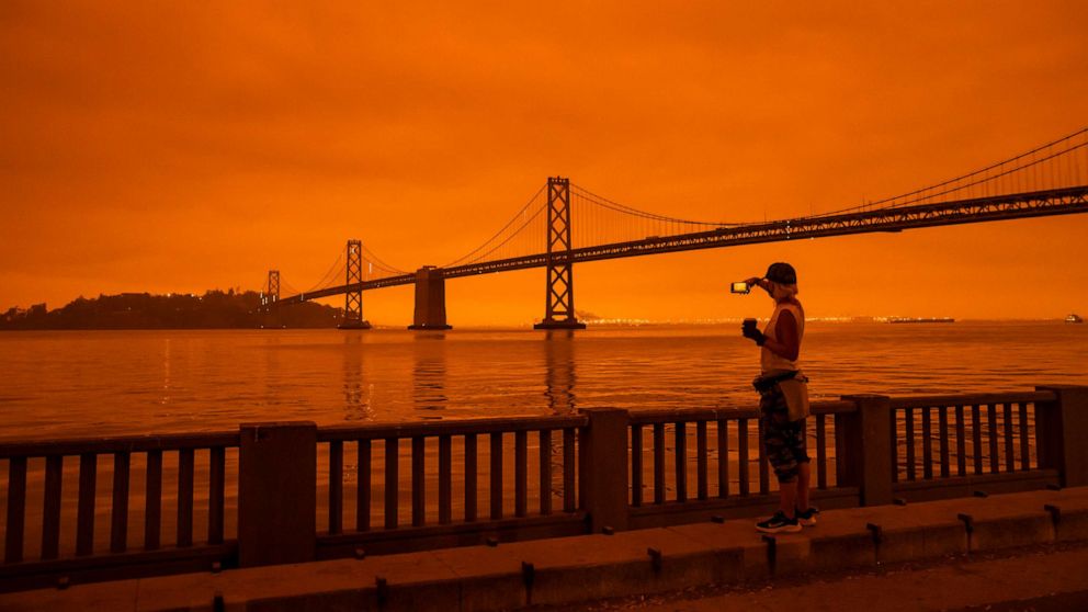 PHOTO: In this Sept. 9, 2020, file photo, a person takes in the view from the Embarcadero as smoke from various wildfires burning across Northern California mixes with the marine layer, blanketing San Francisco in darkness and an orange glow.