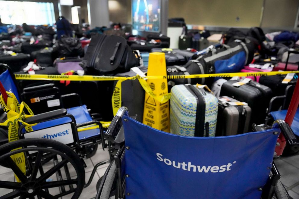 PHOTO: Wheelchairs and caution tape restrict access the baggage claim area and piles of luggage inside the Southwest Airlines terminal at St. Louis Lambert International Airport, Dec. 28, 2022, in St. Louis.