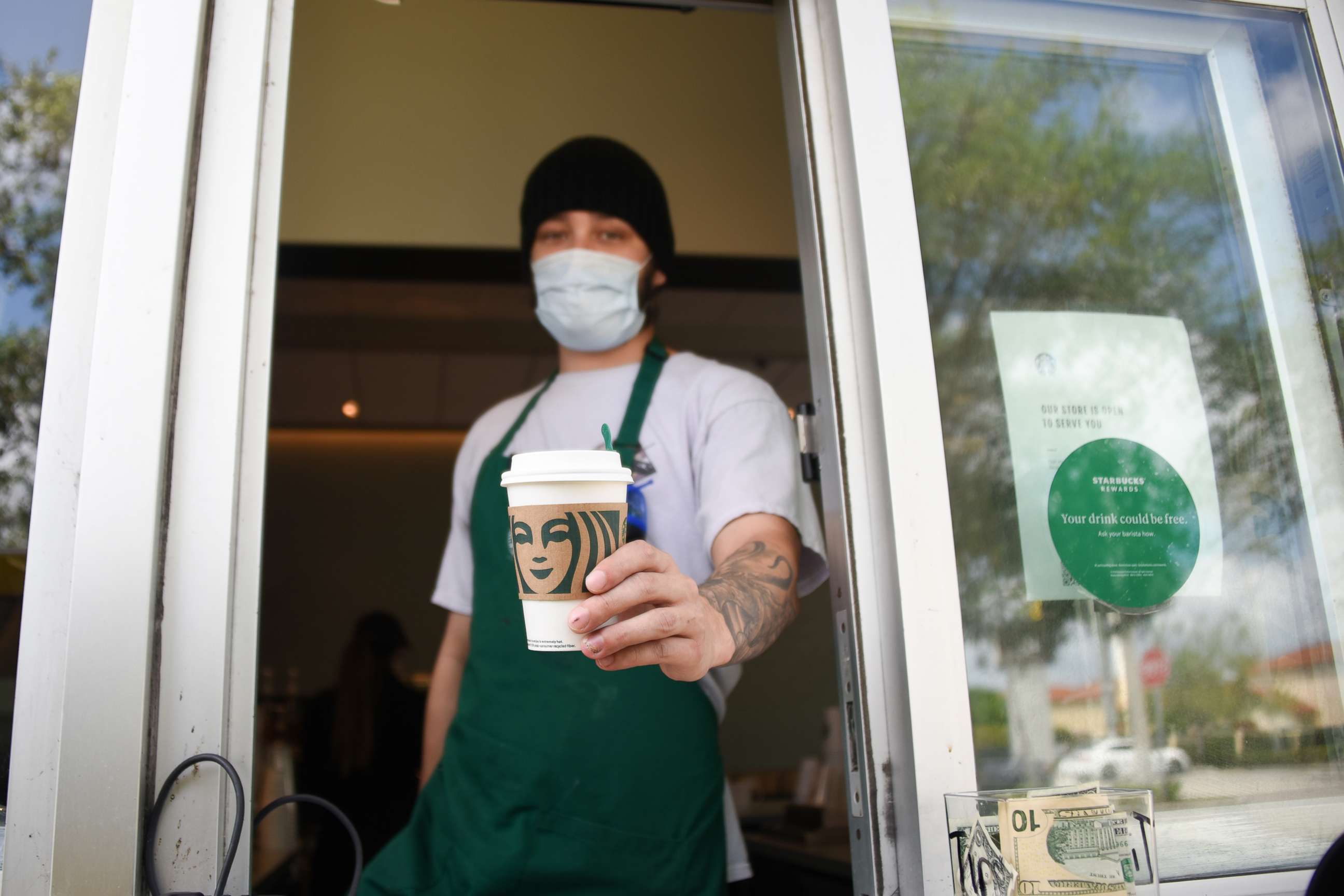 PHOTO: A Starbucks employee wears a mask at the drive thru window in Miami, during the Covid-19 outbreak, April 7, 2020.