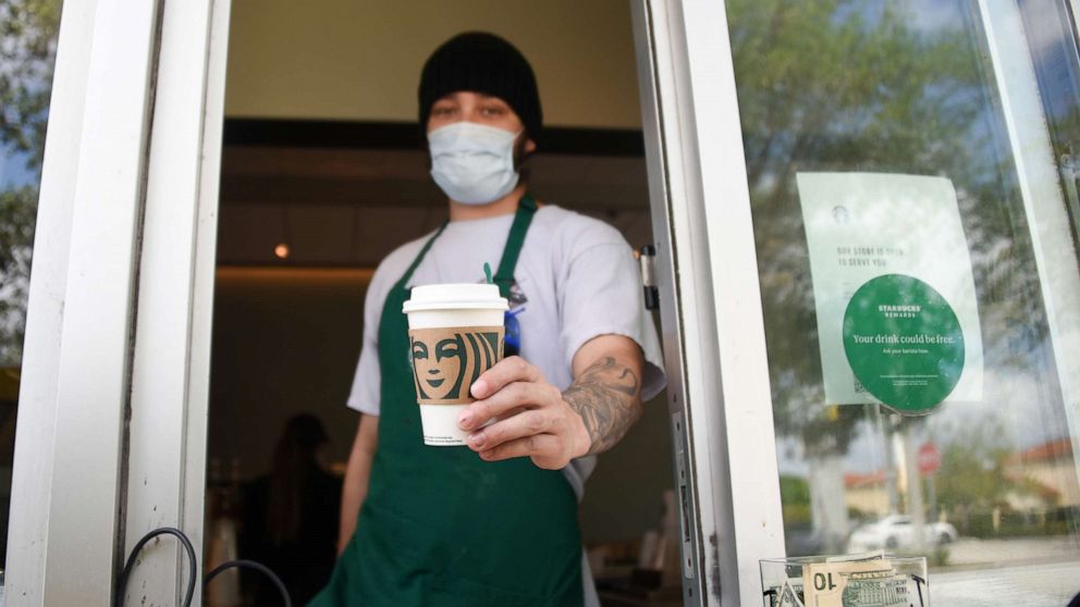 PHOTO: A Starbucks employee wears a mask at the drive thru window in Miami, during the Covid-19 outbreak, April 7, 2020.