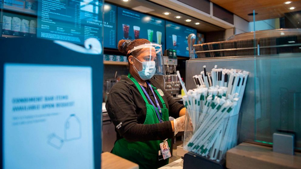 PHOTO: A Starbucks employee wears a face shield and mask as she makes a coffee in Ronald Reagan Washington National Airport in Arlington, Virginia, May 12, 2020.