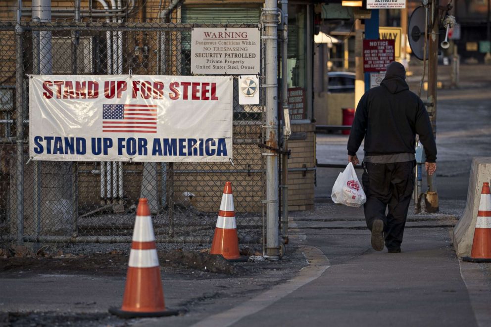 PHOTO: A man walks past a "Stand Up For Steel, Stand Up For America" sign while arriving at the U.S. Steel Corp. Clairton Plant coke manufacturing facility in Clairton, Pa., March 11, 2018.