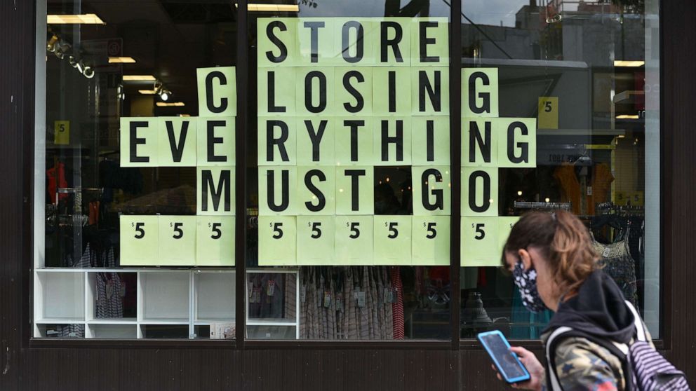 PHOTO: A woman checks her cell phone as she walks past a store closing sign in the Park Slope section of N.Y, Oct. 5, 2020.