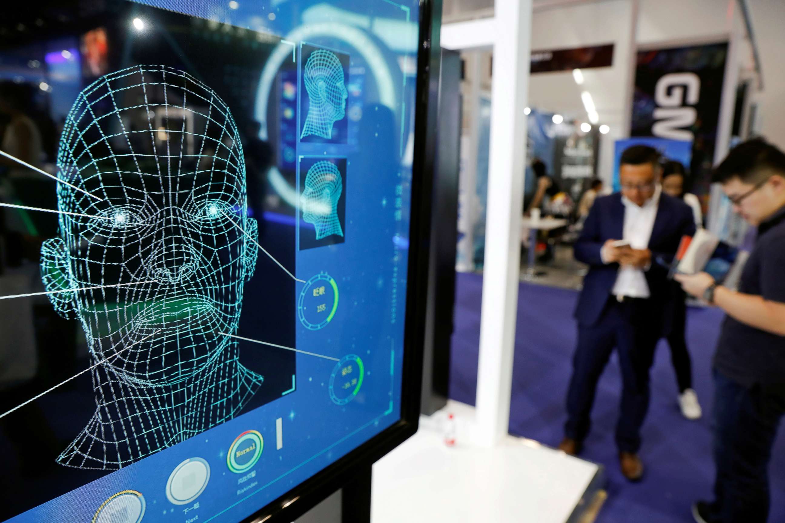 PHOTO: Visitors check their phones behind the screen advertising facial recognition software during Global Mobile Internet Conference (GMIC) at the National Convention in Beijing, Aril 27, 2018.