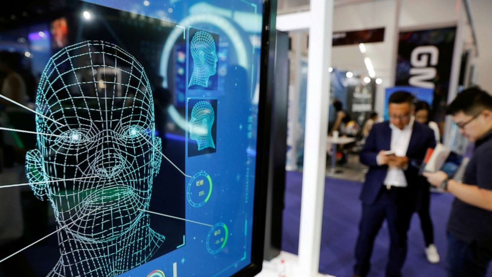 PHOTO: Visitors check their phones behind the screen advertising facial recognition software during Global Mobile Internet Conference (GMIC) at the National Convention in Beijing, Aril 27, 2018.