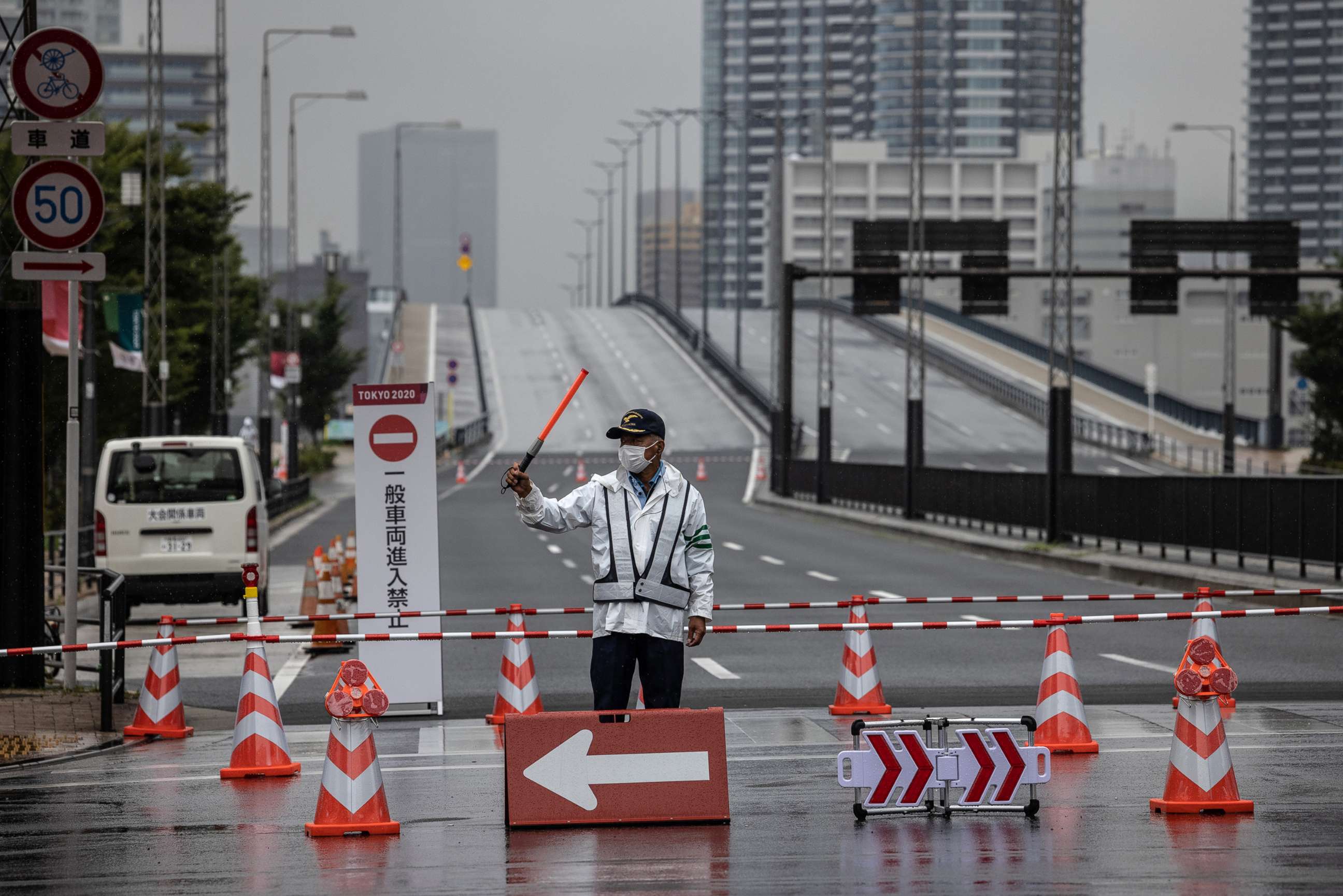 PHOTO: A security guard directs traffic at a blocked on the road leading to Toyosu Ohashi Bridge after it was restricted to Olympic vehicles only, July 8, 2021 in Tokyo, Japan.