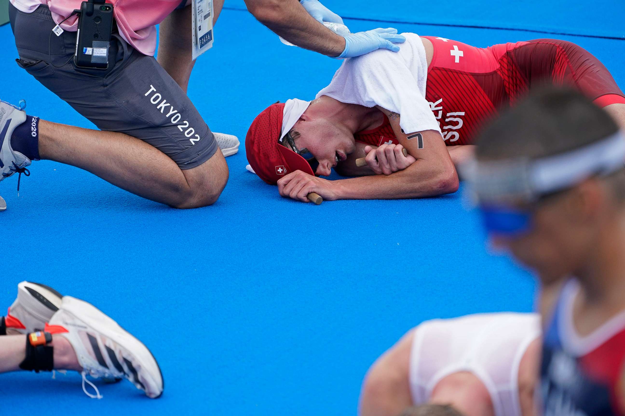 PHOTO: Max Studer, of Switzerland, is tended to after collapsing along with several other athletes, after finishing the men's individual triathlon at the 2020 Summer Olympics, July 26, 2021, in Tokyo.