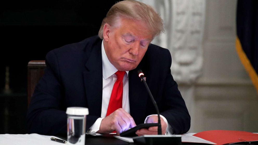 PHOTO: President Donald Trump looks at his phone during a roundtable with governors on the reopening of America's small businesses, in the State Dining Room of the White House in Washington.