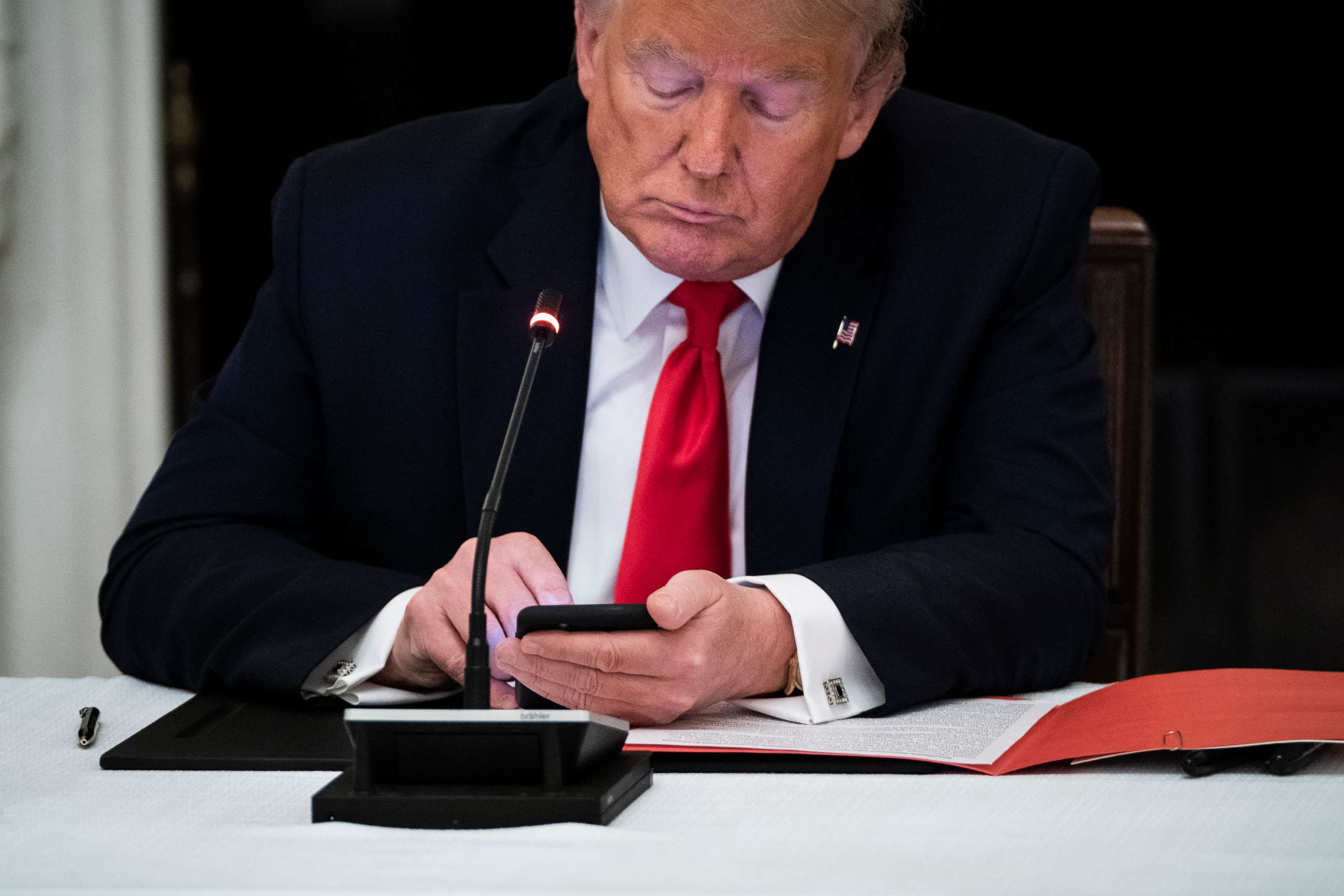 PHOTO: President Donald J. Trump uses his cellphone as he participates in a roundtable discussion in the State Dinning Room at the White House, June 18, 2020. 