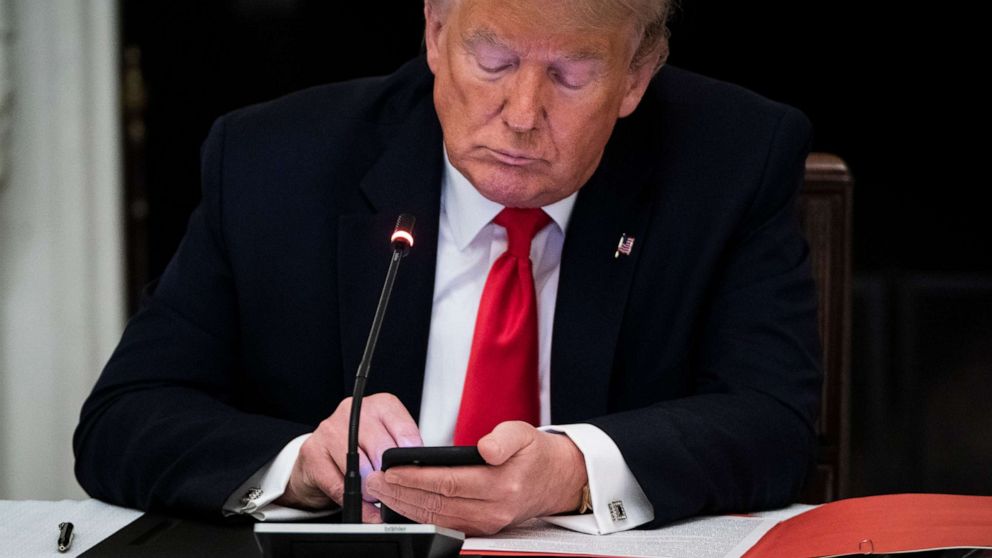 PHOTO: President Donald J. Trump uses his cellphone as he participates in a roundtable discussion in the State Dinning Room at the White House, June 18, 2020. 