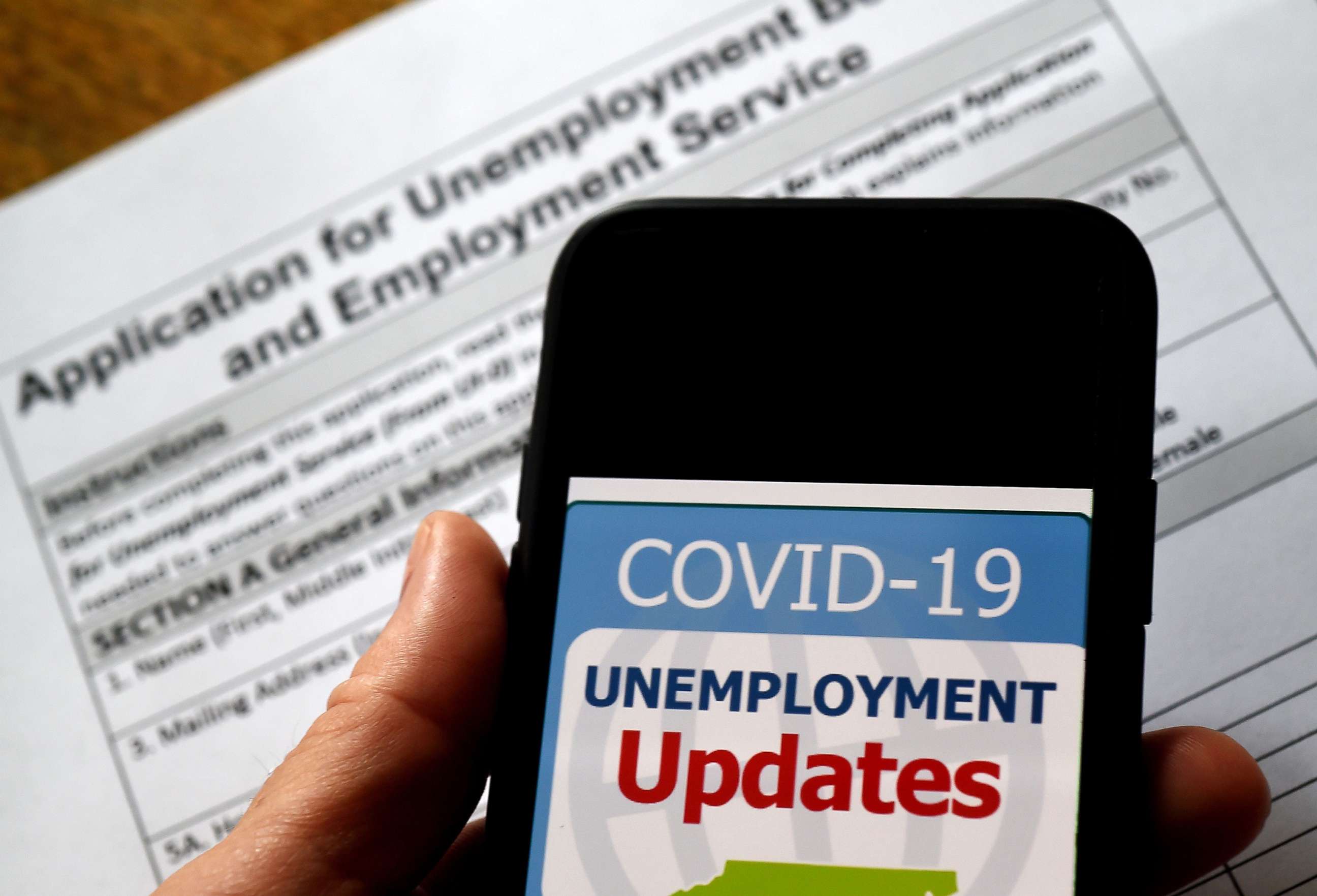 PHOTO: A COVID-19 Unemployment Assistance Updates logo is displayed on a smartphone on top of an application for unemployment benefits on May 8, 2020, in Arlington, Va.