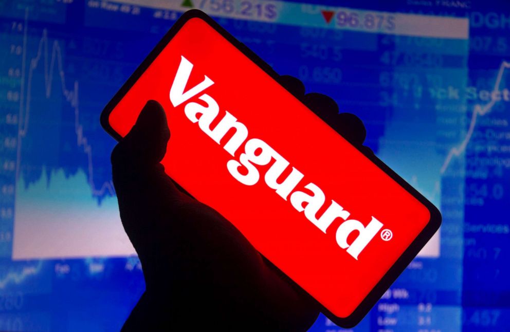PHOTO: In this photo illustration the Vanguard Group logo displayed on a smartphone screen and a stock market graph in the background.