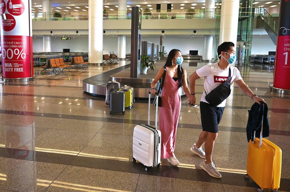 PHOTO: Passengers with protective facemasks walk with their luggage in the mostly empty arrival hall of Noi Bai International Airport in Hanoi, Vietnam, on Feb. 27, 2020.