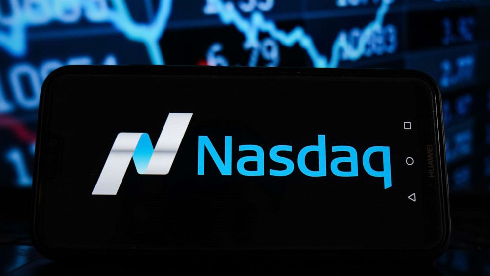 PHOTO: The Nasdaq logo is displayed on a smartphone with stock market percentages in the background in a Photo Illustration.