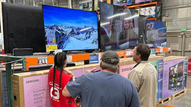 Shoppers consider a large-screen television with the help of a sales associate in a Costco warehouse Thursday, May 1, 2025, in Sheridan, Colo. (AP Photo/David Zalubowski)