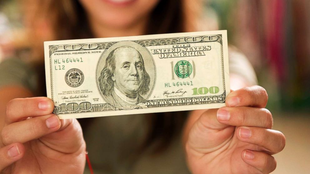 PHOTO: A woman holds a $100 bill in an undated stock photo.