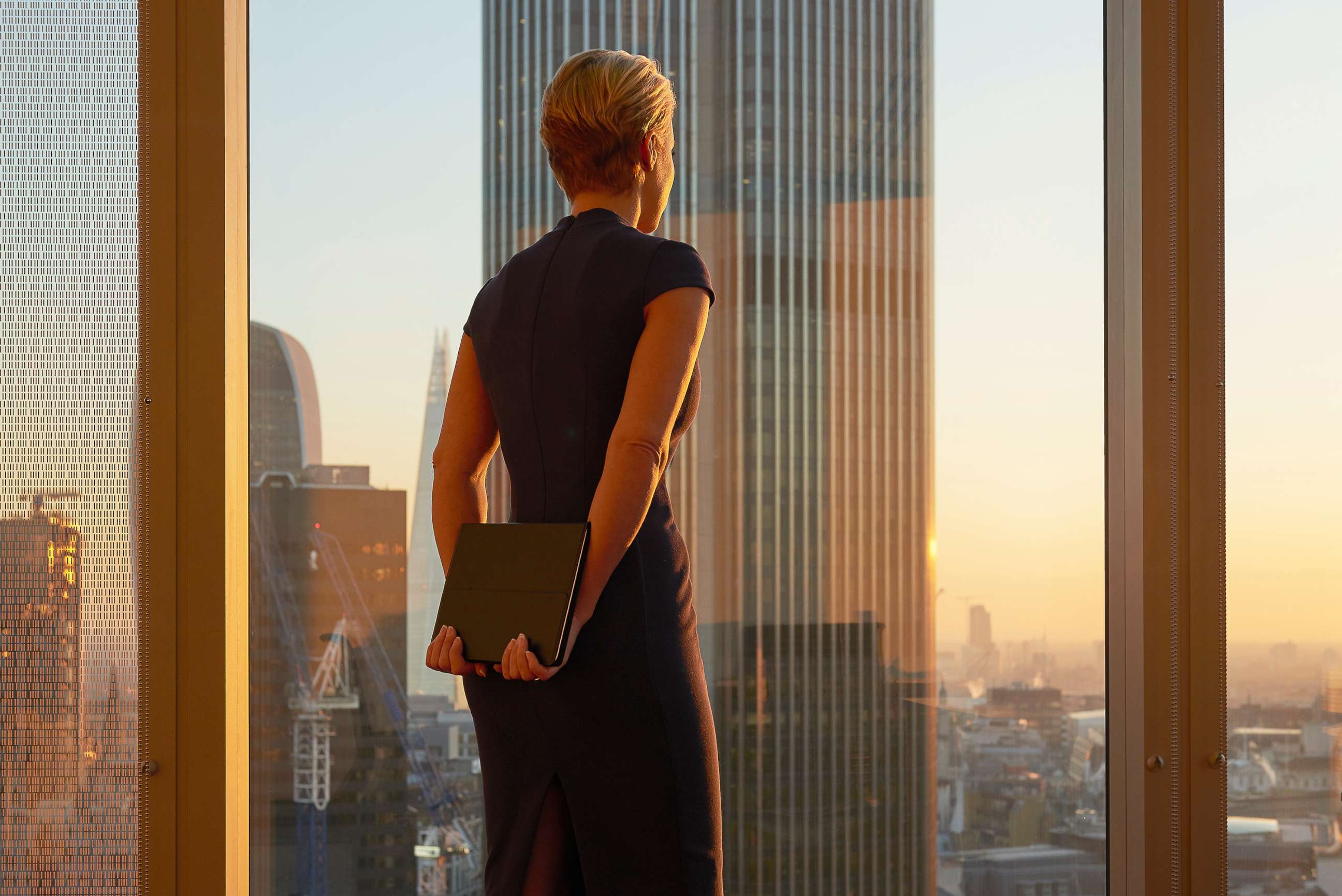 PHOTO: Woman in office standing at window.