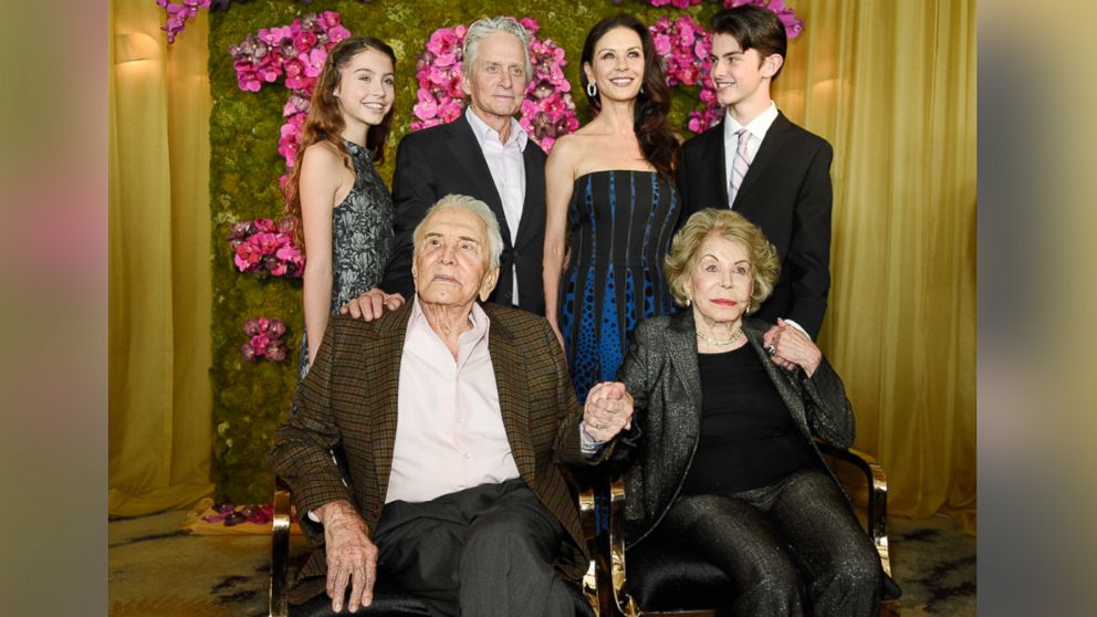 Actor Kirk Douglas, seated left, holds hands with his wife Anne Douglas, seated right, as they pose with family members, their son Michael, standing second left standing, his wife Catherine Zeta-Jones, standing second right standing, and their children, Carys Zeta Jones, left, and son Dylan during Kirk's 100th birthday party at the Beverly Hills Hotel, Dec. 9. 2016, in Beverly Hills, California. 