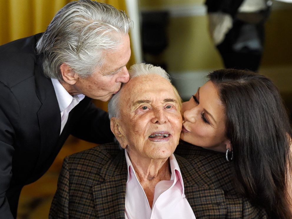 PHOTO: Actor Kirk Douglas, center, gets a kiss from his son Michael Douglas, left, and Michael's wife Catherine Zeta-Jones during his 100th birthday party at the Beverly Hills Hotel on Friday, Dec. 9. 2016, in Beverly Hills, California.