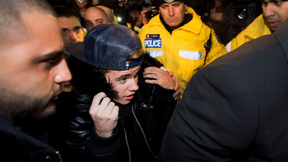 Justin Bieber is swarmed by media and police officers as he enters a police station in Toronto, Jan. 29, 2014.