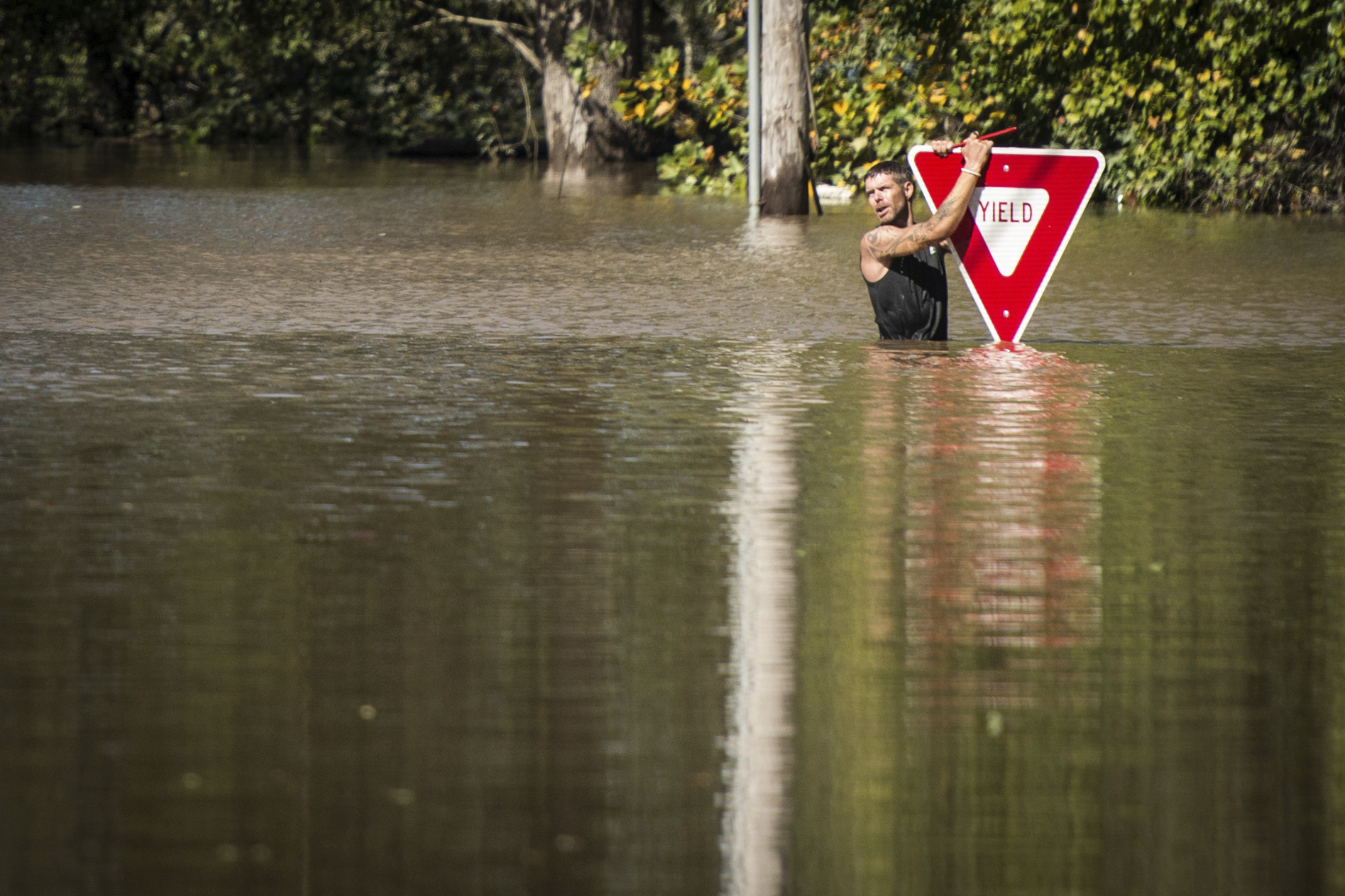 PHOTO: A man holds onto a yield sign after trying to swim out to help a stranded truck driver at NC 301 Highway and Tom Starling Road in Hope Mills, North Carolina, on Oct. 9, 2016. 