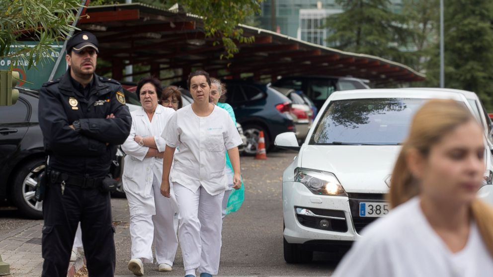 Hospital staff walk out past police guarding the entrance to a protest outside the Carlos III  hospital in Madrid, Spain, Oct. 7, 2014, where a Spanish nurse who is believed to have contracted the ebola virus is being treated.