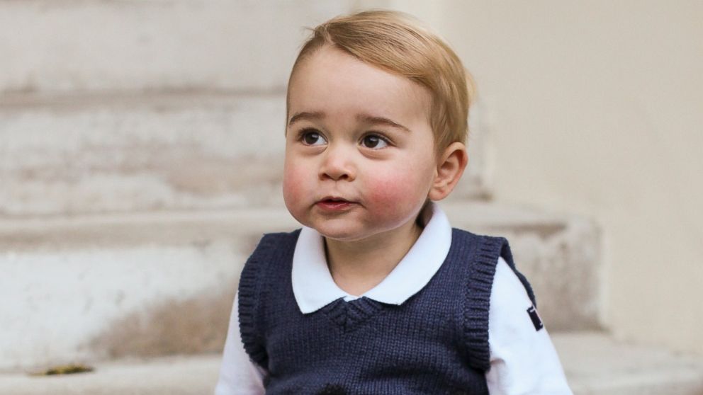 In this photo provided by The Duke and Duchess of Cambridge and taken in late Nov. 2014, Britain's Prince George poses for a photograph in a courtyard at Kensington Palace, London.  