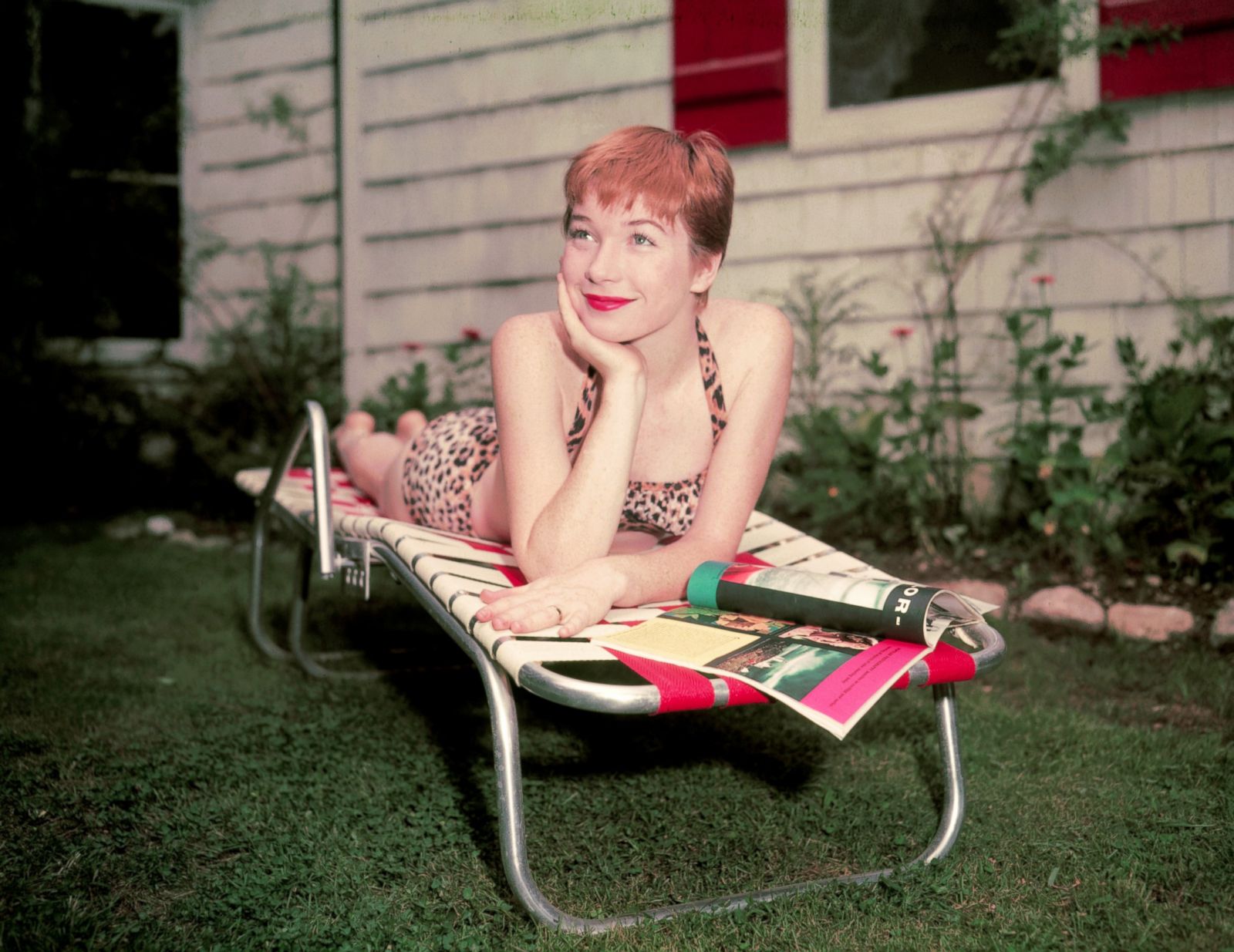 View Shirley MacLaine relaxes on a lounge chair while reading a magazine. p...