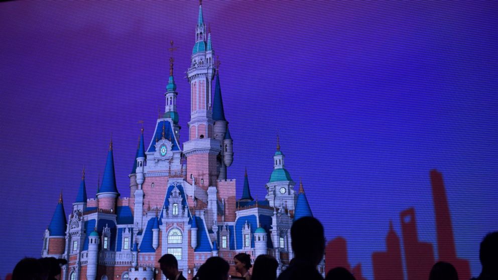 People stand in front of a picture of the planned castle for the Shanghai Disney Resort during a press event in Shanghai, July 15, 2015.