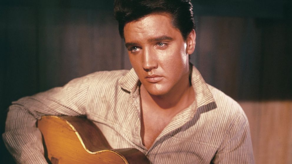 A portrait of Elvis Presley holding an acoustic guitar circa 1956.  