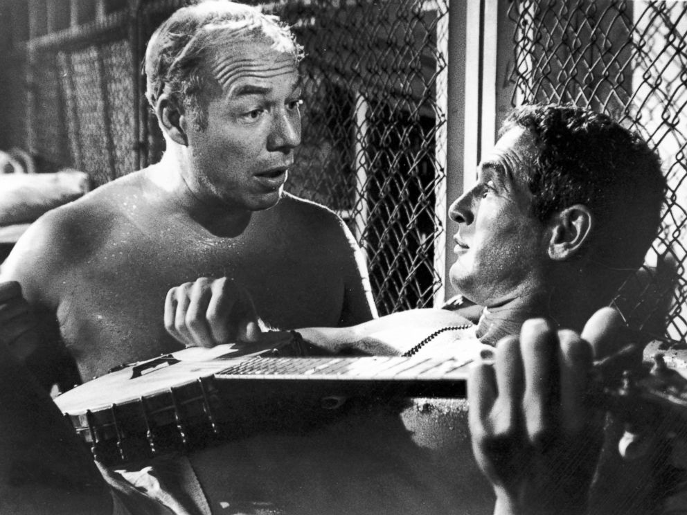 PHOTO: Paul Newman, playing a banjo, and George Kennedy talk in a still from the film Cool Hand Luke.