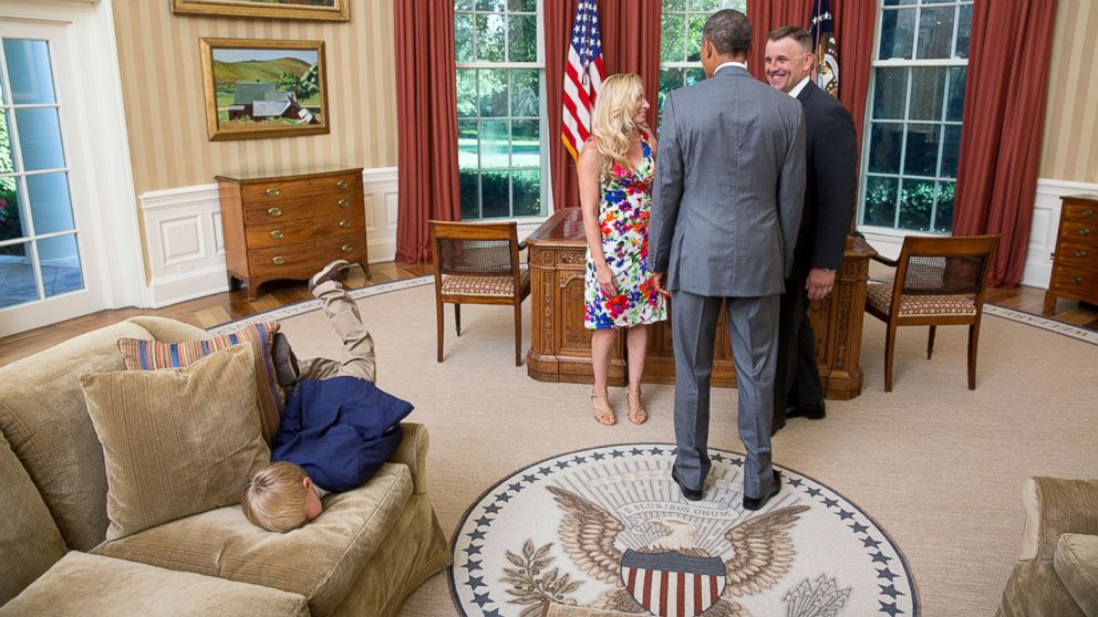 President Obama visits with a departing U.S. Secret Service agent and his wife as their son dives into a couch in the Oval Office, June 23, 2014. 