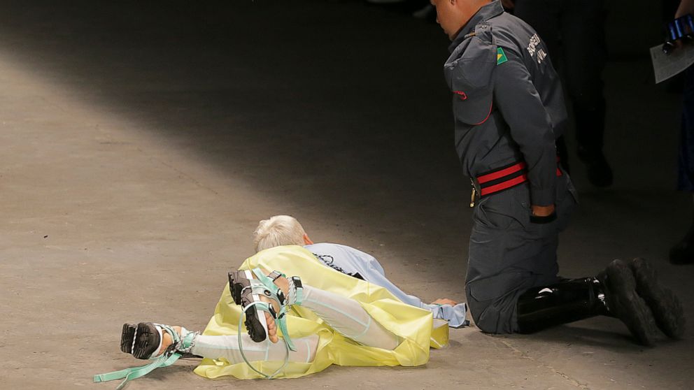 Model Tales Soares lies on the catwalk as a paramedic tends to him after he collapsed during Sao Paulo Fashion Week in Sao Paulo, Brazil, Saturday, April 27, 2019. A statement from organizers said that Soares died after taking ill while participating