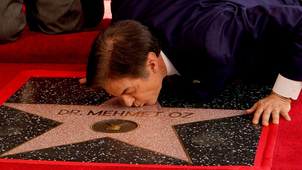 Mehmet Oz, the former host of "The Dr. Oz Show," kisses his new star on the Hollywood Walk of Fame during a ceremony on Friday, Feb. 11, 2022, in Los Angeles. (AP Photo/Chris Pizzello)