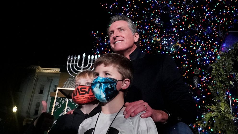 California Gov. Gavin Newsom poses for a photo with a pair of youngsters after the 90th annual State Capitol Tree Lighting Ceremony in Sacramento, Calif., Thursday, Dec. 2, 2021. Newsom has written a children's book inspired by his experiences dealin
