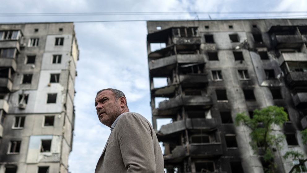 American actor Liev Schreiber stands in front of a house which have been destroyed by Russia bombardment in Borodianka, near Kyiv, Ukraine, on Monday, Aug. 15, 2022. (AP Photo/Evgeniy Maloletka)