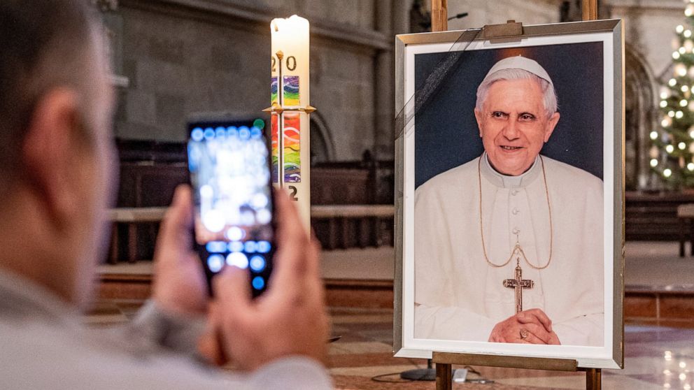 A person takes a picture of a portrait of Pope Emeritus Benedict XVI at St. Peter's Cathedral in Regensburg, Germany, Saturday, Dec. 31, 2022. Pope Emeritus Benedict XVI, the German theologian who will be remembered as the first pope in 600 years to 