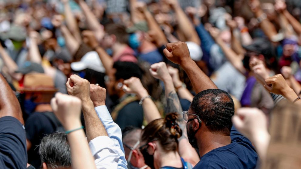 FILE - In this Saturday, May 30, 2020, file photo, demonstrators raise fists in the air during a march in Pittsburgh to protest the death of George Floyd, who died after being restrained by Minneapolis police officers on May 25. A black reporter from