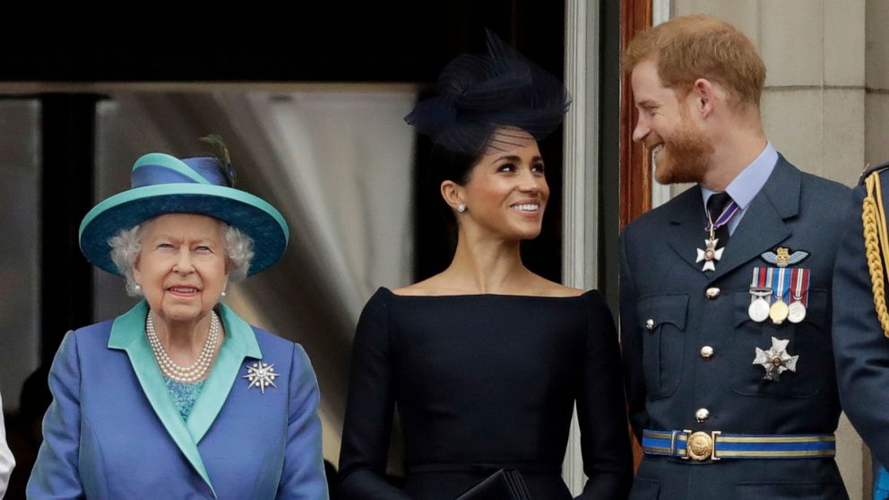 FILE - In this Tuesday, July 10, 2018 file photo Britain's Queen Elizabeth II, and Meghan the Duchess of Sussex and Prince Harry watch a flypast of Royal Air Force aircraft pass over Buckingham Palace in London. As part of a surprise announcement dis