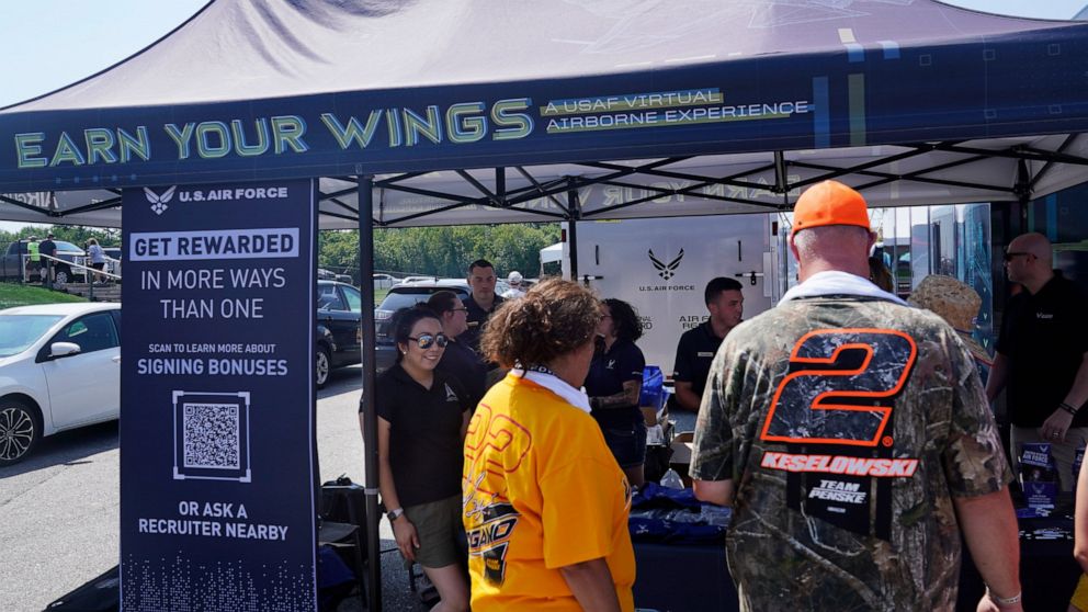 Racing fans stop at the U.S. Air Force recruiting tent prior to a NASCAR race at the New Hampshire Motor Speedway, Sunday, July 17, 2022, in Loudon, N.H. These are tough times for military recruiters.  All services are having problems finding young p