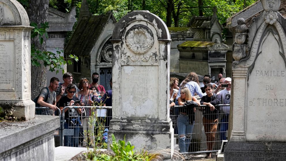 Fans gather at the tomb of rock singer Jim Morrison at the Pere-Lachaise cemetery in Paris, Saturday, July 3, 2021. Fans across Europe gathered at the grave of rock legend Jim Morrison to mark the 50th anniversary of his death.(AP Photo/Michel Euler)
