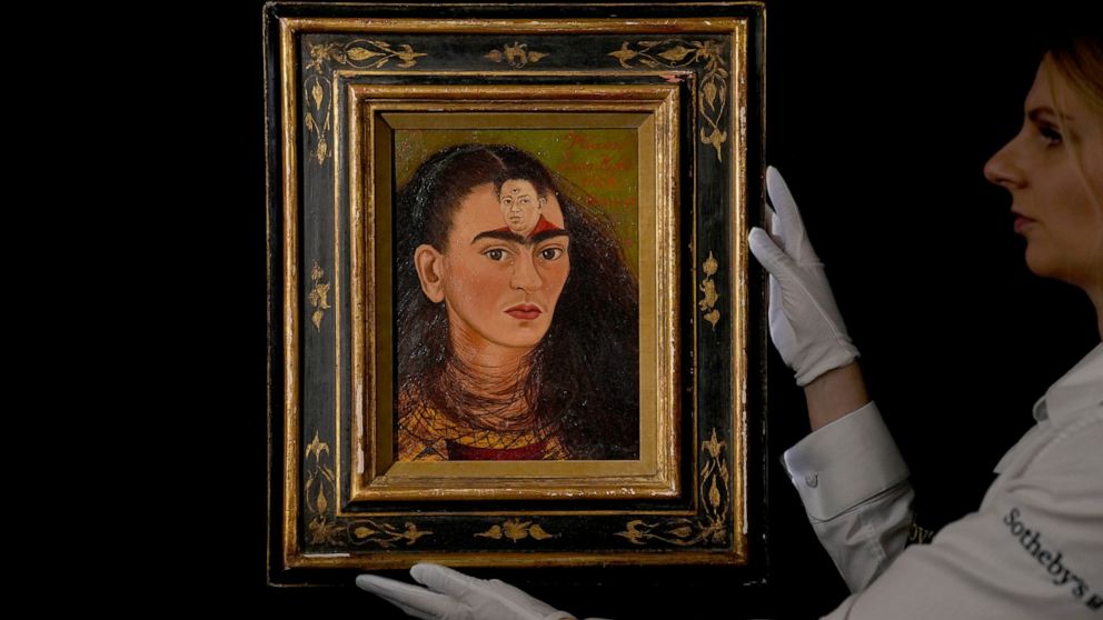 FILE - A staff member poses for photographs with the Mexican painter Frida Kahlo's 1949 self-portrait "Diego y yo", Diego and I, at Sotheby's auction house in London, Thursday, Oct. 21, 2021. The Mexican icon, whose art is as immediate and unsentimen